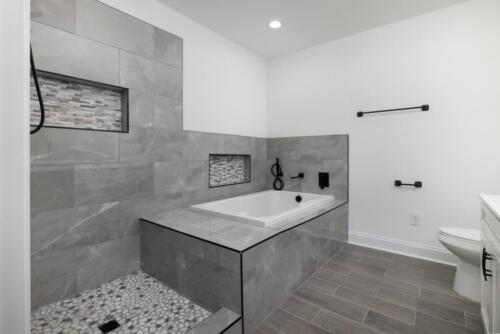Caliber Home Builder, Hickory III, large master bathroom with stone tile shower and separate bathtub.