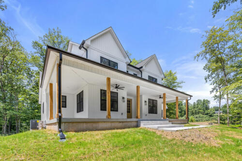 The Corbisiero - elegant farm style home - white exterior with oak porch posts and front door, by Caliber Homebuilder