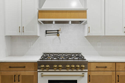 The Corbisiero - elegant farm style home - closeup of oven / stove and range hood in kitchen, by Caliber Homebuilder