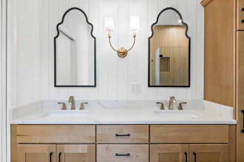 The Corbisiero - elegant full bathroom with natural wood cabinets and double vanity sinks, by Caliber Homebuilder