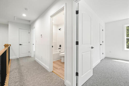 The Corbisiero - view of second floor bedroom and bathroom from hallway, by Caliber Homebuilder