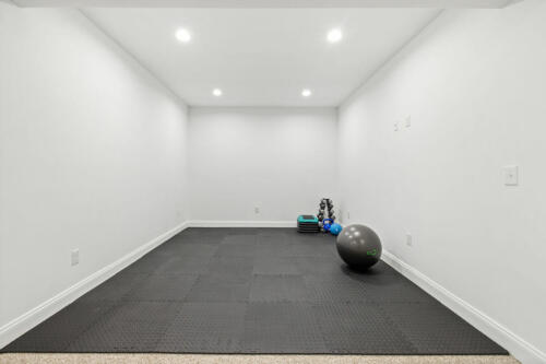The Corbisiero - workout area in basement with black mat flooring, by Caliber Homebuilder